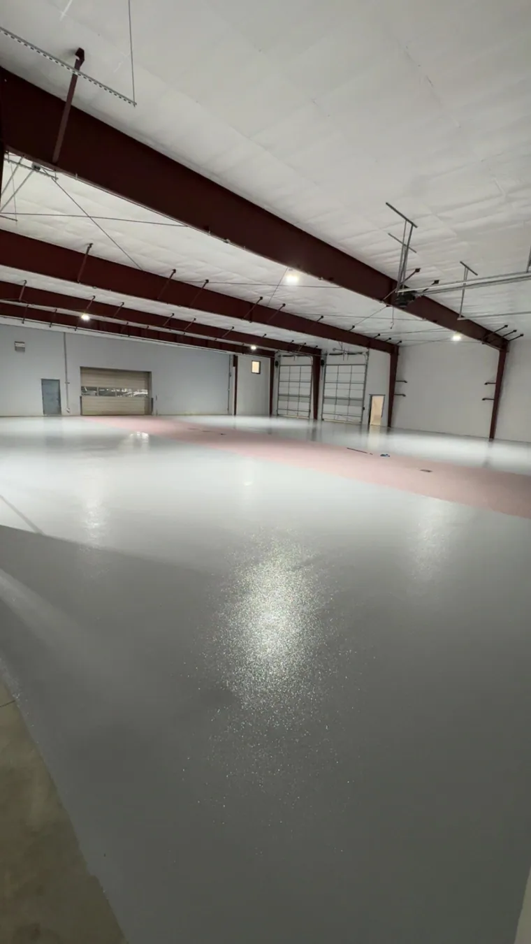 Glossy grey epoxy floor running the length of a commercial warehouse